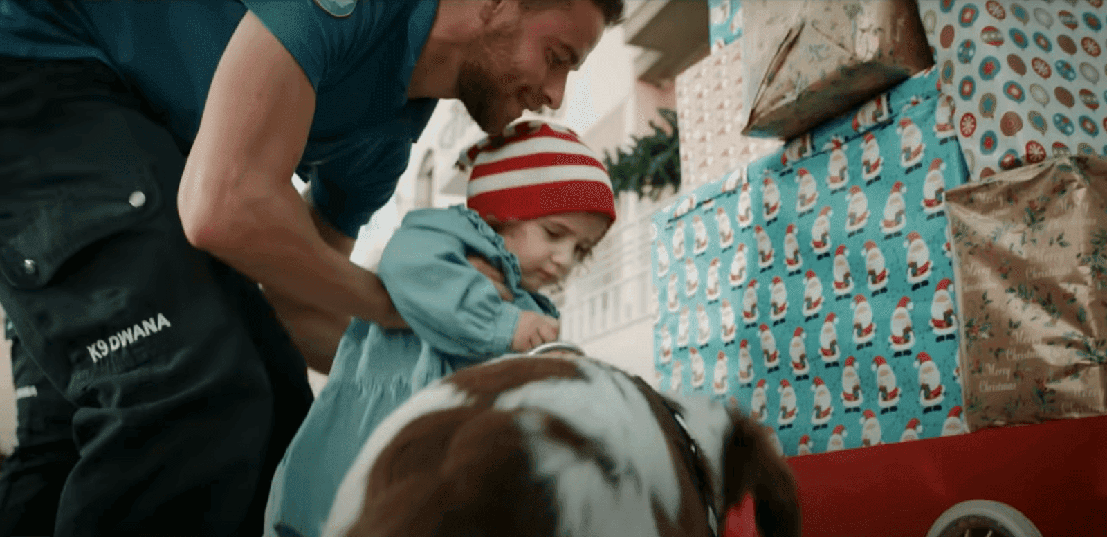 A customs officer, with a k9 dog, helping a young girl