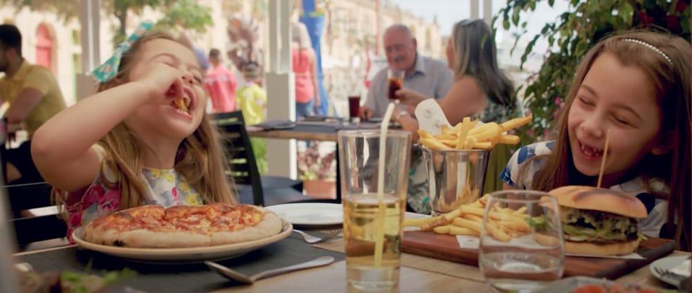 Two girls are eating at a table, one stole a fry from the other in motion blur's commercial